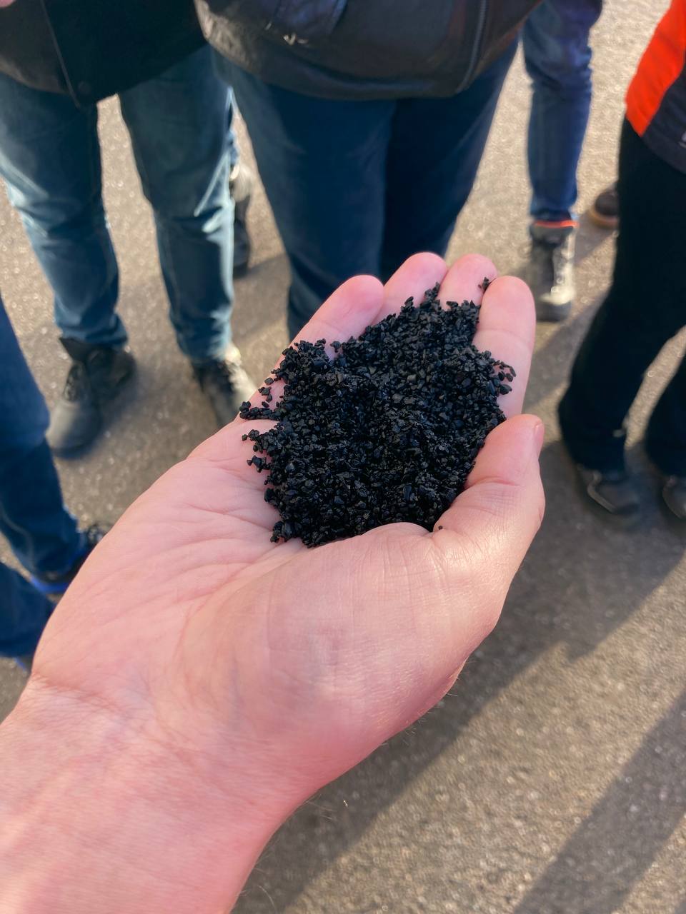 hand holding black aggregate material